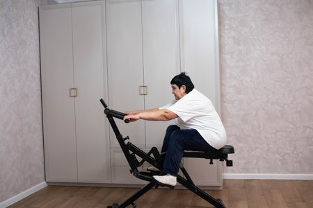 Senior woman exercising at home on an abdominal workout machine, focusing on fitness and maintaining an active, healthy lifestyle in a modern interior.の写真素材