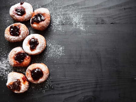 Tasty donuts with jam on wooden background. Sweet icing sugar food. Dessert colorful snack.の写真素材