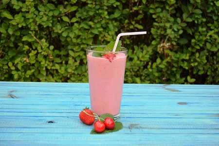glass of strawberries, cherries smoothie with straw on wooden table. Protein cocktail. Healthy drink. Fresh homemade smoothie. Healthy breakfast of smoothie,の写真素材