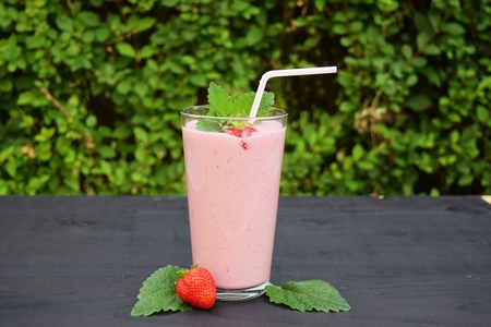 glass of strawberries, cherries smoothie with straw on wooden table. Protein cocktail. Healthy drink. Fresh homemade smoothie. Healthy breakfast of smoothie,の写真素材