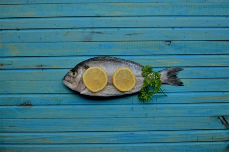 Delicious fresh fish on wood background. Fish with aromatic herbs, spices. Healthy food, diet or cooking conceptの写真素材
