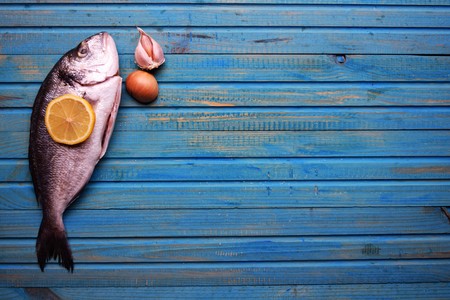 Delicious fresh fish on wood background. Fish with aromatic herbs, spices. Healthy food, diet or cooking conceptの写真素材