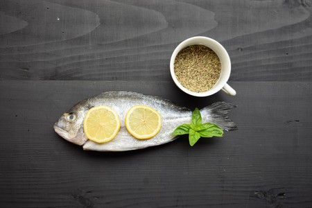 Delicious fresh fish on wood background. Fish with aromatic herbs, spices. Healthy food, diet or cooking conceptの写真素材
