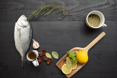 Delicious fresh fish on wood background. Fish with aromatic herbs, spices. Healthy food, diet or cooking conceptの写真素材