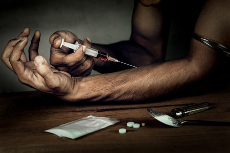 Junkie man holding drug syringe injection heroin to hand.Social disaster and epidemic of narcotic...