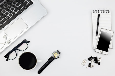 White office desk table with computer,coffee cup,and glasses.Business background with electronic...