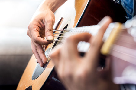 Close up of man's hands playing acoustic guitar. Musical instrument for recreation or hobby passion...