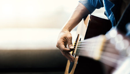 Close up of man's hands playing acoustic guitar. Musical instrument for recreation or hobby passion...