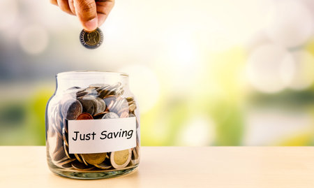 Hand picking up coins into glass jar for save money for business and financial concept.Saving...