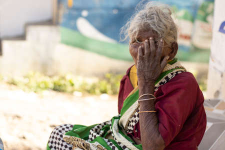 Chennai - Tamilnadu India. 24 July 2020. An old lady sitting with her hands on her mouth, outdoors woman portraitのeditorial素材