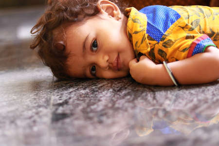 A child looking at the camera on the black marble floorの写真素材