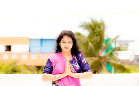 Beautiful Hindu young girl praying with folded hands and open air aroundの写真素材