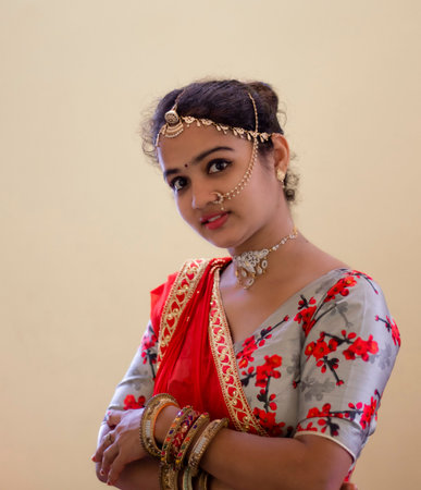 A beautiful young Hindu girl with gold ornaments according to her traditions and customs and red...