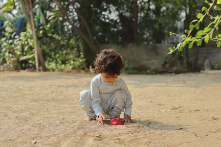 Close-up of An Indian child playing with a red hibiscus flower.の写真素材