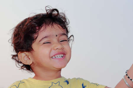 low angle close-up portrait of An Indian child smiling with eyes closedの写真素材