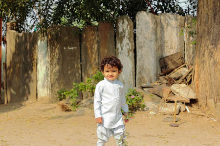 An Indian child smiling at the camera standing in front of the courtyard outside .の写真素材