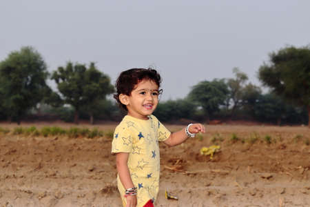low angle close-up portrait of An Indian child stands in the field looking at the cameraの写真素材