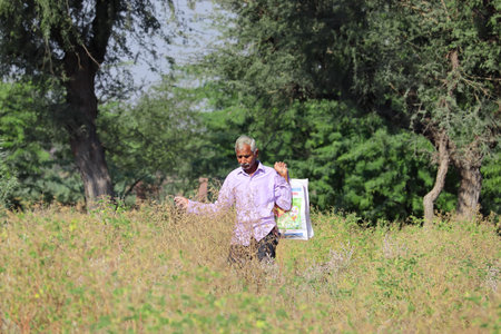 Closeup portrait photo of An Indian senior hindu man, holding a bag in his hand, passes through the...