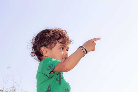 Close-up portrait of an indian fair little hindu boy child showing a distant object with finger gestures with wearing green t-shirt , indiaの写真素材