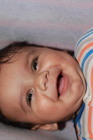 Close-up of An indian little newborn innocent boy baby smiling looking at the camera indoor