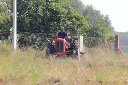 An Indian male laborer farmer plowing the field with the help of a tractor plowのeditorial素材