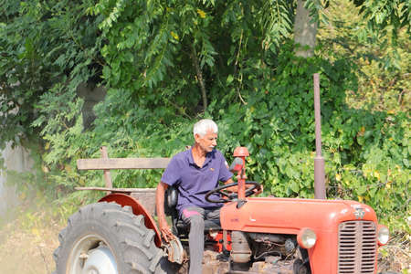 âPali Rajasthan, India. âNovember 04 ,â2021. An Indian senior farmer plowing the field with sitting on a tractorのeditorial素材