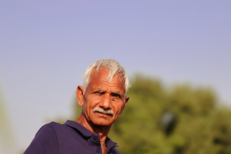 Close-up portrait Photo of an Indian farmer with blue sky backgroundの写真素材