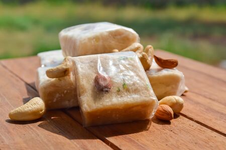 Patisa / Soan Papdi is a popular Indian cube shape flakey/crispy dessert.sonpapdi and nuts on wooden tableの写真素材