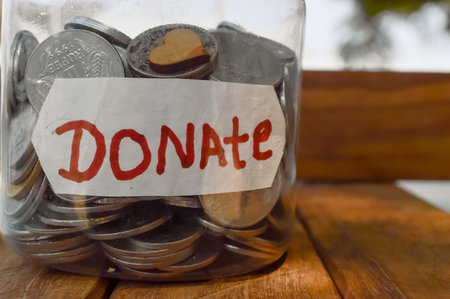 charity box written text of donate and jar in money and small hard,donate written text,wooden table...