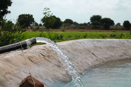 Water coming out of a tube well and flowing in the agricultural fields,water pump and tank with a huge flow of fresh water for irrigating fields,farming conceptの写真素材
