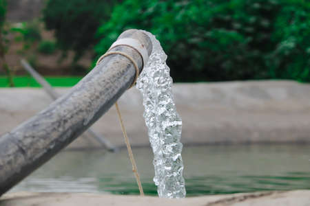 Pumping water out of plastic pipe into the ground,Water from a well filled a pond for irrigation,Irrigation water from the source,Water flow from large pump tube in Farm,being flush out a heavy tube,の写真素材