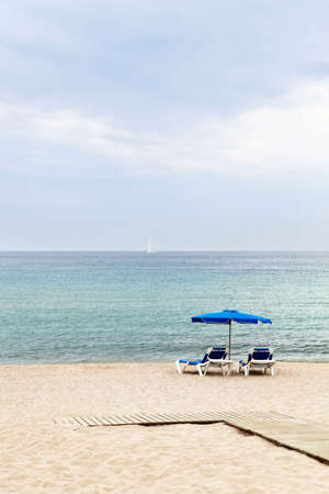 Two lounges and umbrella at tranquill seasideの写真素材