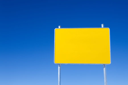 Blank bright yellow road sign on clear blue sky backgroundの写真素材