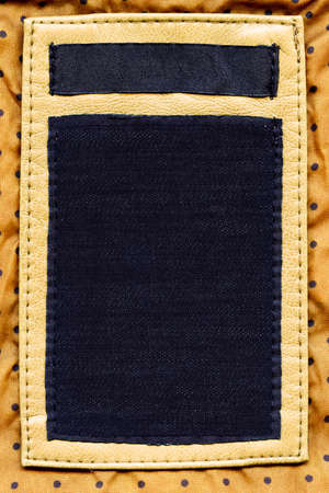 Big size blank grungy combined artificial leather and dark cotton and jeans label on yellow dotted textile background の写真素材
