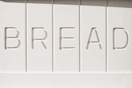 The word "BREAD" inscripted on a white wooden bread box sideの写真素材