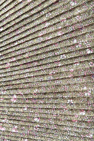 Abstract background made of pleated textile of pastel colors floral motives