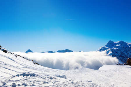 Sun and clouds over winter mountains, covered with snowの写真素材