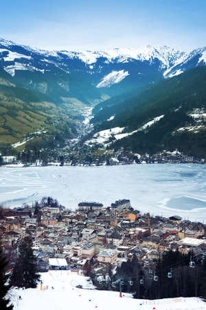 Aeral view down on Zell Am See (Austria, Alpes) town, frozen lake, ski resort and mountains in fog.の写真素材