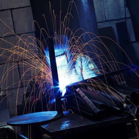 Worker wearing protective face mask welding metal details 
