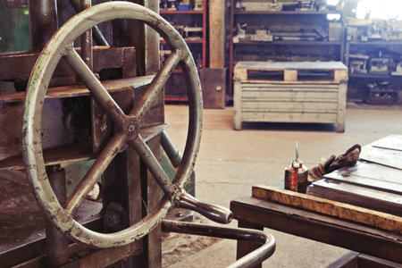An old factory interior and a part of obsolete heavy machinery with control metal wheel