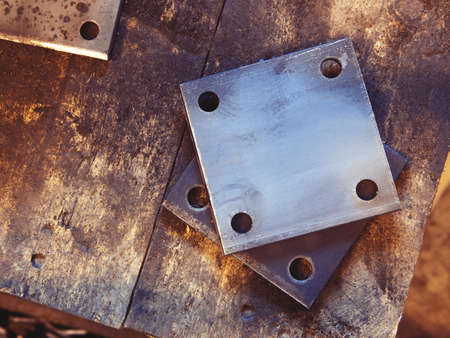 Grunge rusty rectangle metal plates with round holes placed on wooden textured boardの写真素材