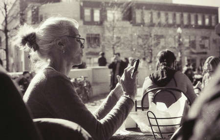 Beautiful elderly woman texting somebody on her phoneの素材