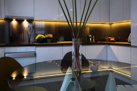 Interior - white modern kitchen and a glass dining table with chairsの写真素材