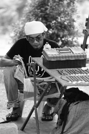 Asian man selling handmade necklace at a roadside stand