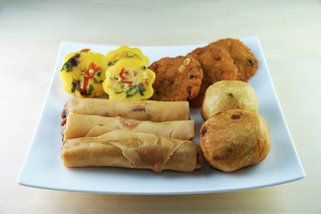 Assorted Malay traditional food on a white plate - Kuih Cara Berlauk, Cucur Badak, Popiah, Vadehの写真素材