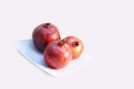 Three Pomegranate Fruit or Buah Delima on a square white plateの写真素材