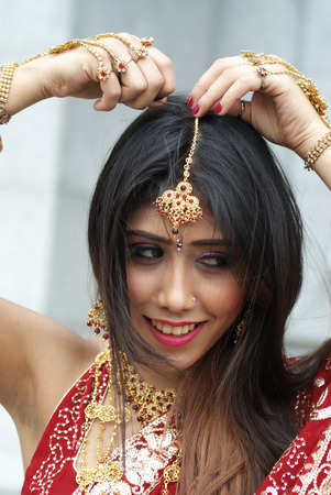 Young Indian girl in red traditional saree clothing fixing her hair pinの写真素材