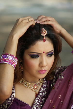 Young Indian girl in purple traditional saree clothing fixing her hair pinの写真素材