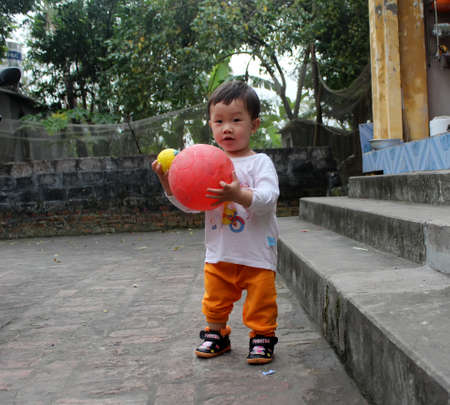 HAI DUONG, VIETNAM, September, 2: Asian boy about 1 year old, play football alone in the yard on September, 2, 2013 in Hai Duong, Vietnam.のeditorial素材