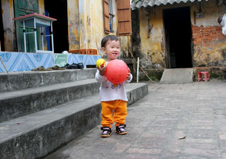 HAI DUONG, VIETNAM, September, 2: Asian boy about 1 year old, play football alone in the yard on September, 2, 2013 in Hai Duong, Vietnam.のeditorial素材